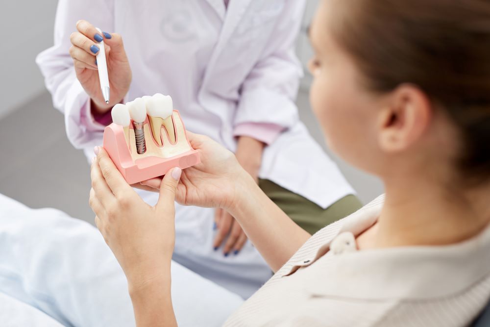 A prosthodontist teaching a patient about dental implants.