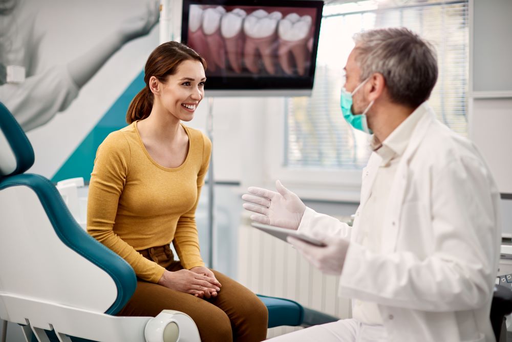 A dentist speaking with his patient and recommending a few preventive dental tips for her to try at home.