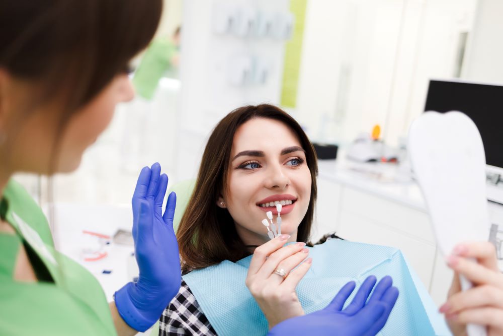 A dentist helping a patient decide on colors for veneers and sharing some helpful tips to properly maintain those veneers.