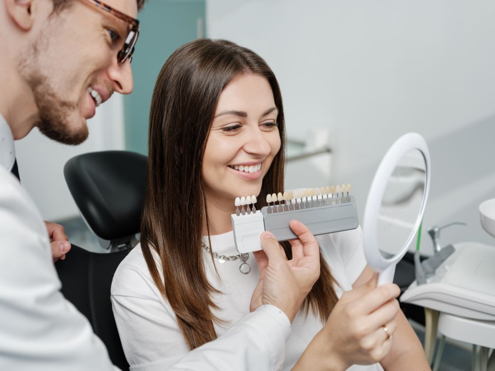A dentist showing his patient the different styles of veneers that she can get.
