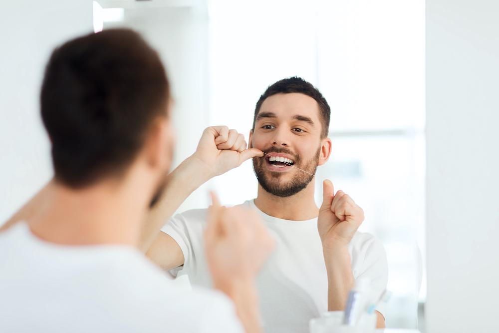 Man cleaning his teeth using dental floss