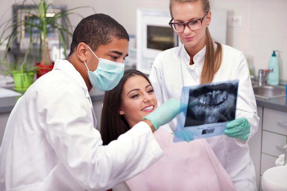 Dentists showing female patient her teeth xray